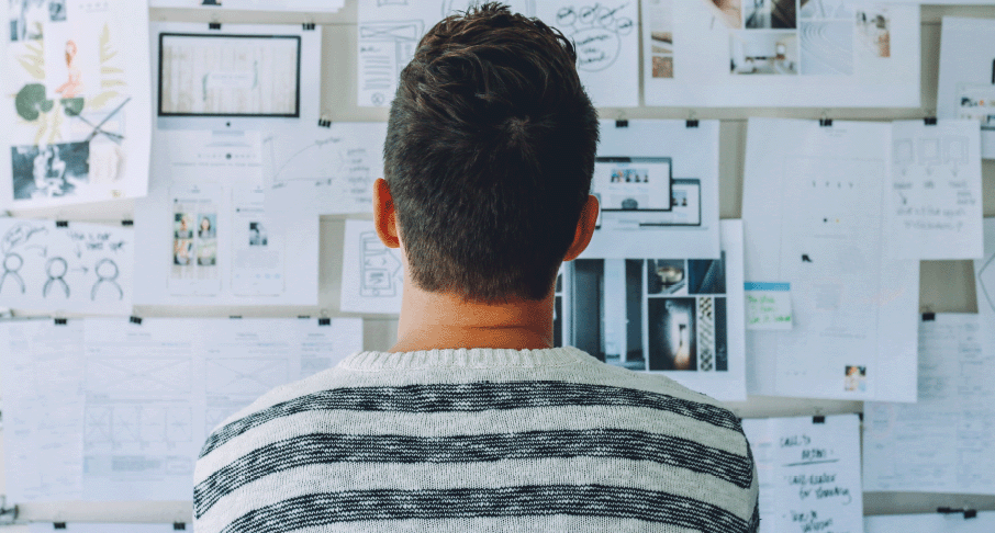 person looking at wall of papers